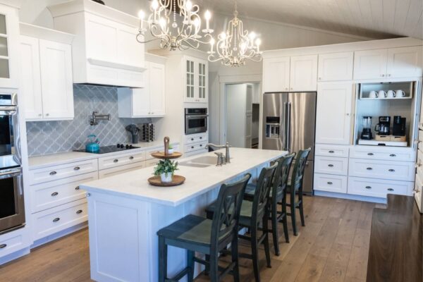 A bright kitchen featuring elegant white cabinets and a stylish chandelier hanging from the ceiling
