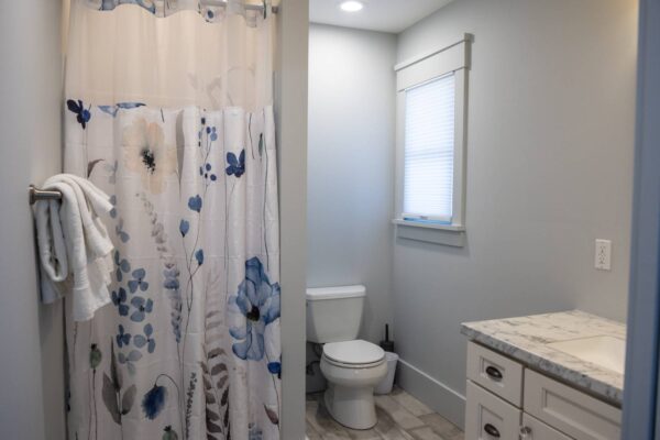 A clean bathroom featuring a shower curtain and a toilet, showcasing a simple and functional design