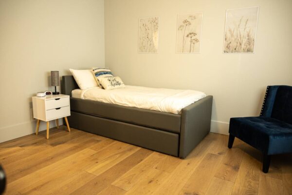 A cozy bedroom featuring a bed, a chair, and a table, creating a warm and inviting atmosphere