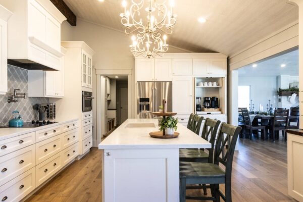 A modern kitchen adorned with pristine white cabinets and a beautiful chandelier providing ambient lighting