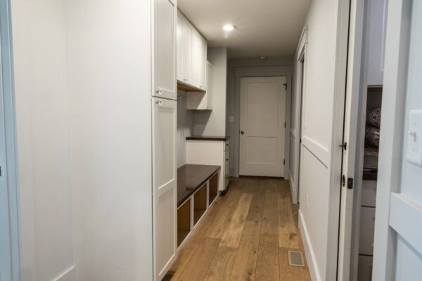 A spacious hallway adorned with white cabinets and rich wooden floors, offering a clean and stylish aesthetic