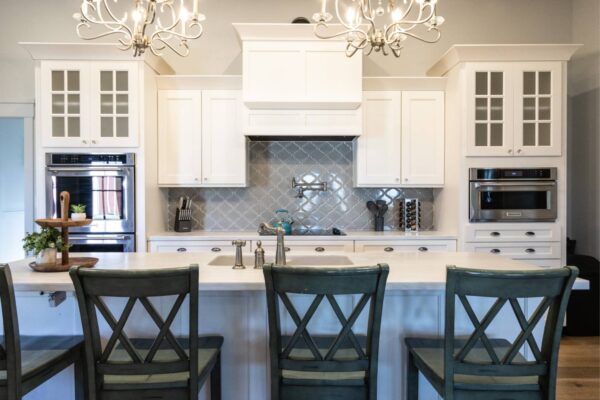 A spacious kitchen showcasing sleek white cabinetry complemented by a stunning chandelier overhead