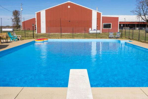 A vibrant blue pool positioned before a traditional barn, offering a peaceful view of rural life